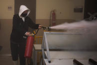 Supporters of rap singer Pablo Hasél use fire extinguishers against police officers entering at the University of Lleida, Spain, Tuesday, Feb. 16, 2021. A rapper in Spain and dozens of his supporters have locked themselves inside a university building in the artist's latest attempt to avoid a prison sentence for insulting the monarchy and praising terrorism. (AP Photo/Joan Mateu)