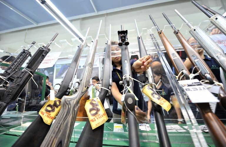 This file photo shows shop employees arranging rifles for sale at a gun show in Manila, on July 15, 2010. There were 1.2 million registered firearms in the Philippines as of last year, according to data from the police firearms and explosives office. There were another roughly 600,000 unlicensed firearms in circulation across the Philippines, according to the office's records