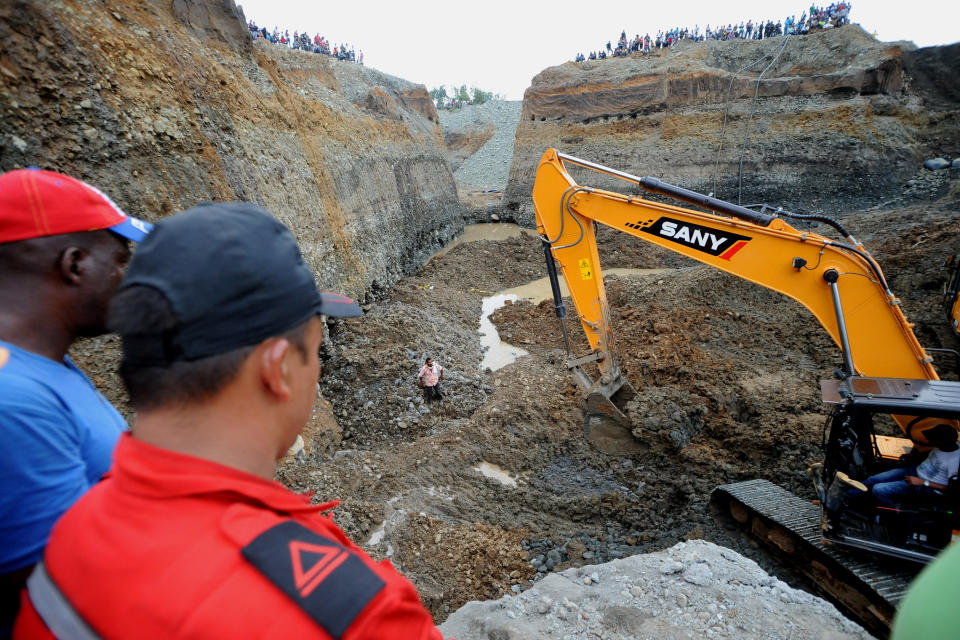 People watch as machinery is used to search for survivors of a collapsed illegal gold mine in Santander de Quilichao, southern Colombia, Thursday, May 1, 2014. The bodies of three miners have been recovered and an unknown number remain missing, said Temistocles Ortega, governor of the Cauca state. (AP Photo/Oswaldo Paez, El Pais)