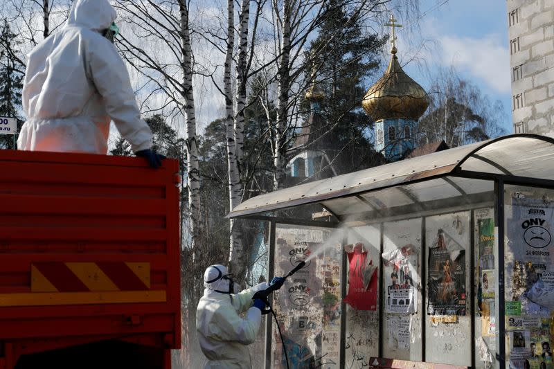 FILE PHOTO: A specialist wearing protective gear sprays disinfectant while sanitizing a bus stop in Vsevolozhsk