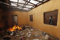 A Christian man passes by a burning pile at a mosque in Fouh district in Bangui December 10, 2013. The French army said it has restored some stability in the capital of Central African Republic after battling gunmen on Monday in an operation to disarm rival Muslim and Christian fighters responsible for killing hundreds since last week. REUTERS/Emmanuel Braun (CENTRAL AFRICAN REPUBLIC - Tags: CIVIL UNREST MILITARY POLITICS RELIGION TPX IMAGES OF THE DAY CONFLICT)