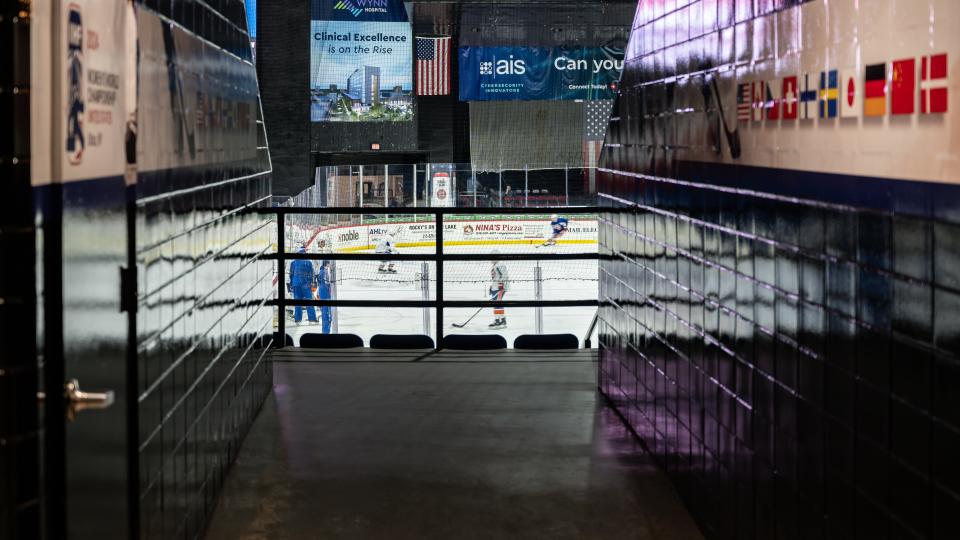 An interior view of the Adirondack Bank Center with international flags displayed along the runway leading out to the rink.