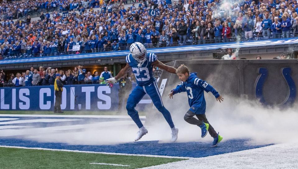 Colts cornerback Kenny Moore ran onto thie field with Mason Garvey before  the start of a game against the Denver Broncos at Lucas Oil Stadium.