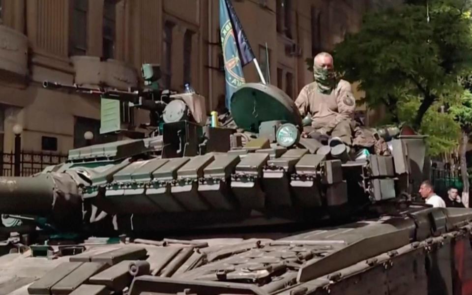 In this image from video, a man sits atop an armoured vehicle in a street in Rostov on Saturday