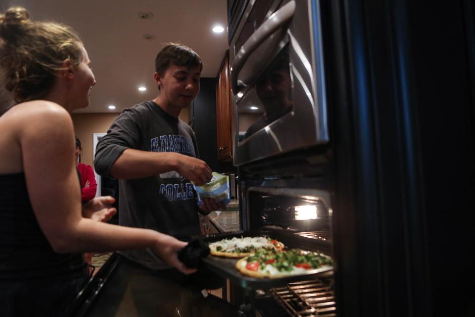 Will Rhodunda checks on the family's pizza dinner with his sister Alexa in their Wilmington, Del., home on June 12.