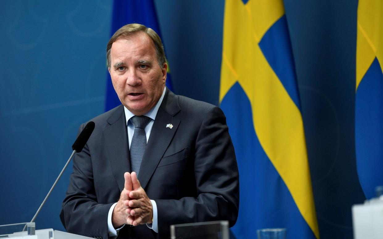 Sweden's leader Stefan Lofven gives a speech in front of a row of Swedish flags - TT NEWS AGENCY