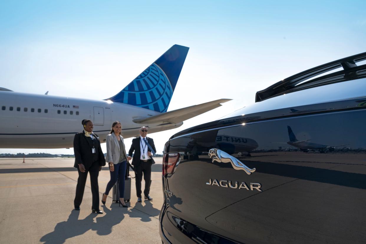 The tail of a United Airlines jet and the trunk of a Jaguar on the tarmac.