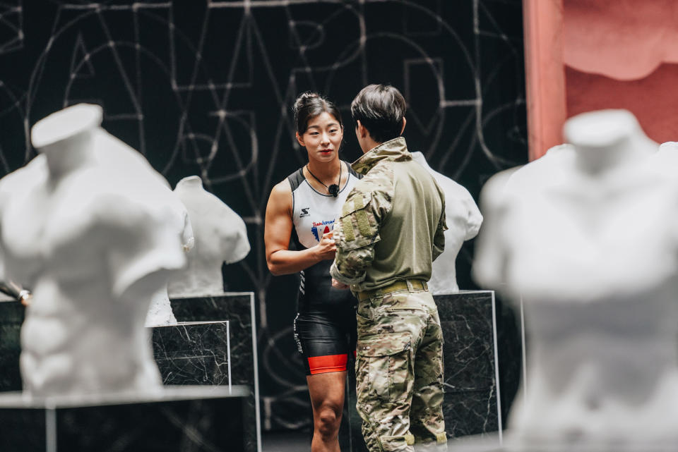 jang eun-sil and another contestant chat while flanked by torso busts, in 'physical: 100' season 1