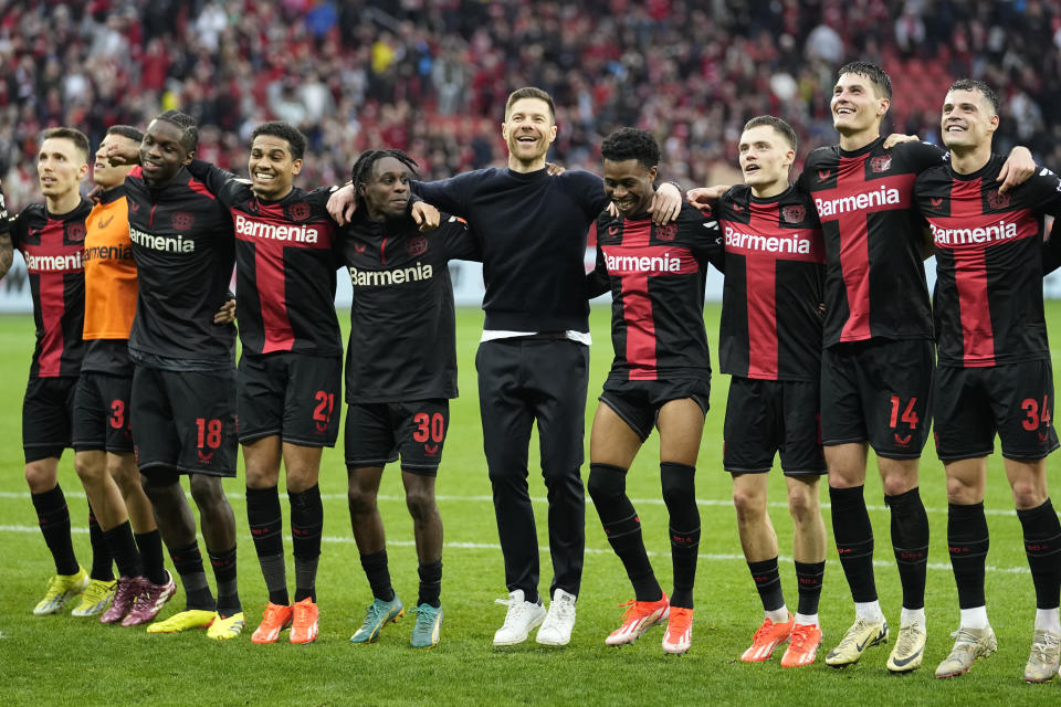 Leverkusen's head coach Xabi Alonso, center, celebrates with his team in front of supporters after winning the German Bundesliga soccer match between Bayer Leverkusen and TSG Hoffenheim at the BayArena in Leverkusen, Germany, Saturday, March 30, 2024. (AP Photo/Martin Meissner)