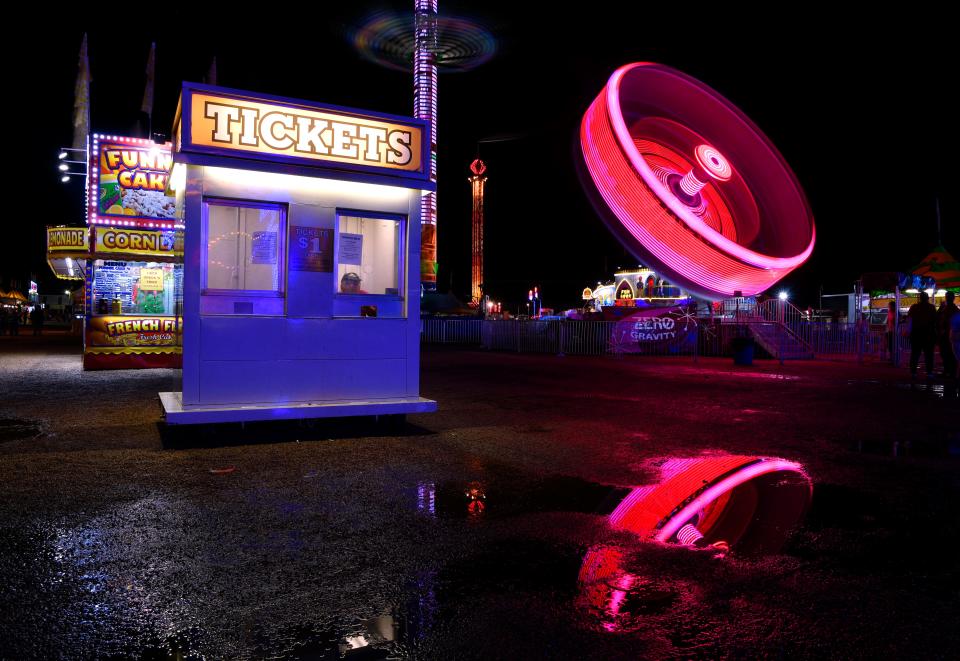 A salesman sits in the window of a ticket booth at the West Texas Fair & Rodeo as the Zero Gravity ride spins in the background in 2018.
