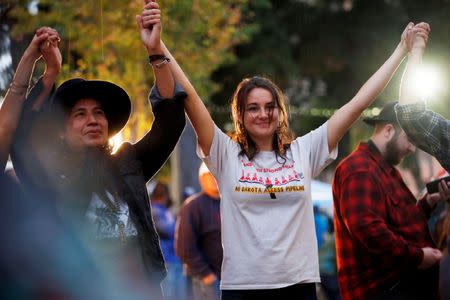 Actor Shailene Woodley (C) holds hands into the air with Lehi Thundervoice Eagle Sanchez (L) during a prayer circle at a climate change rally in solidarity with protests of the pipeline in North Dakota at MacArthur Park in Los Angeles, California October 23, 2016. REUTERS/Patrick T. Fallon