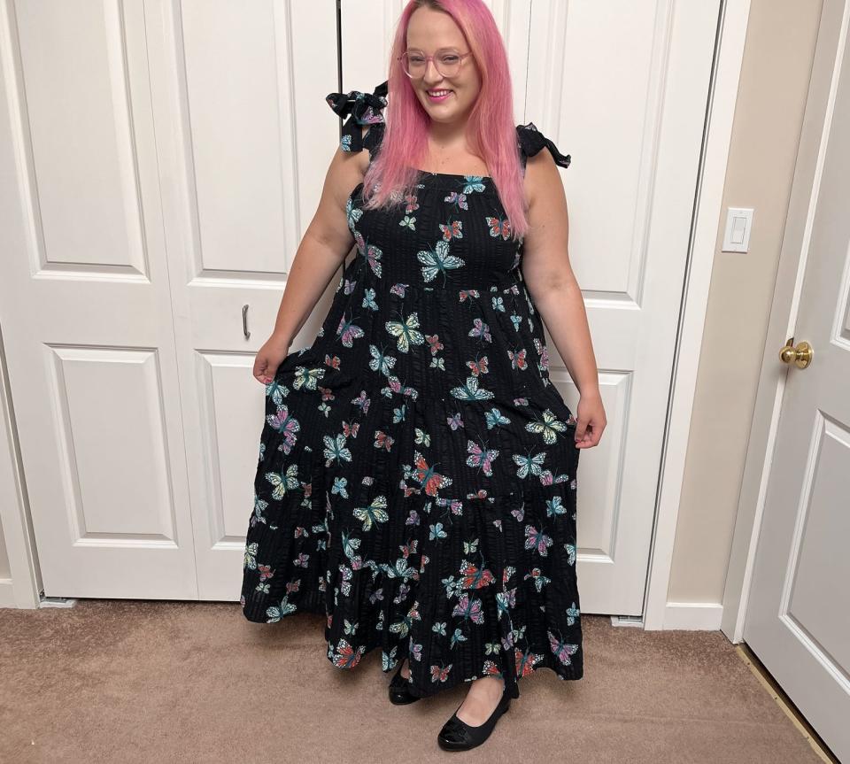 The writer wearing a maxi-length black butterfly-print dress