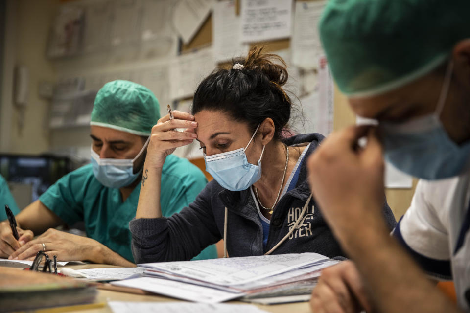 In this photo taken on Friday, April 10, 2020 nurse Cristina Settembrese talks with colleagues during the night meeting at the end of her work shift in the COVID-19 ward at the San Paolo hospital in Milan, Italy. (AP Photo/Luca Bruno)