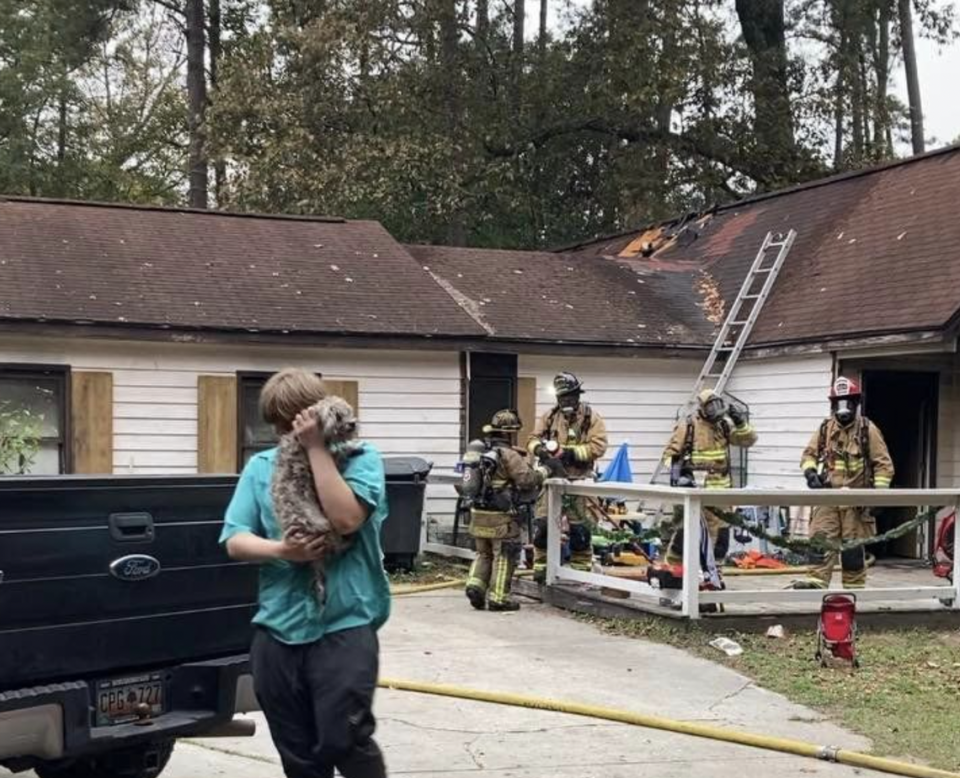 A dog is carried away from a home on Broad River Boulevard following a house fire Friday afternoon.