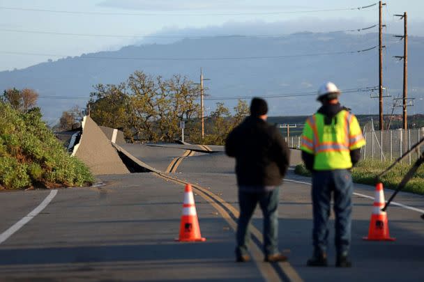 PHOTO: A Pacific Gas and Electric (PG&E) worker looks at a road that buckled when it was undermined by a mudslide during a Bomb Cyclone storm earlier in the week on March 23, 2023 in Novato, Calif. (Justin Sullivan/Getty Images)