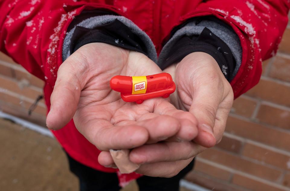 Sam Dlott, 23, aka Hammy Sammy, holds a wiener whistle as he stands next to Oscar Mayer's Wienermobile on Friday, March 22, 2024, during a snow day in Shelby Township.