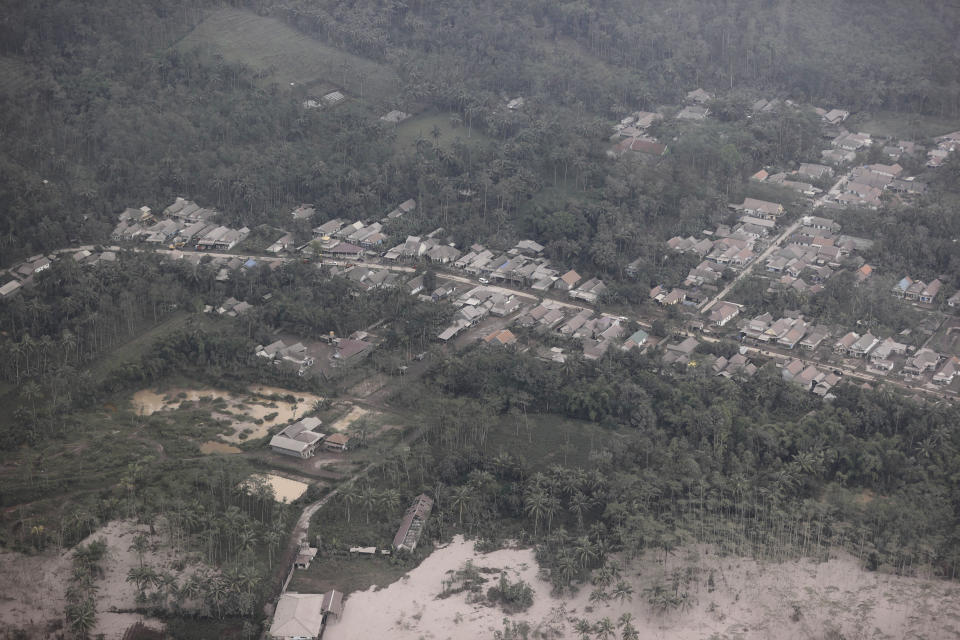 A village is covered by ash from the eruption of Mount Semeru in Lumajang district, East Java province, Indonesia, Sunday, Dec. 5, 2021. The death toll from eruption of the highest volcano on Indonesia's most densely populated island of Java has risen with scores still missing, officials said Sunday as rain continued to pound the region and hamper the search.(AP Photo/Trisnadi)