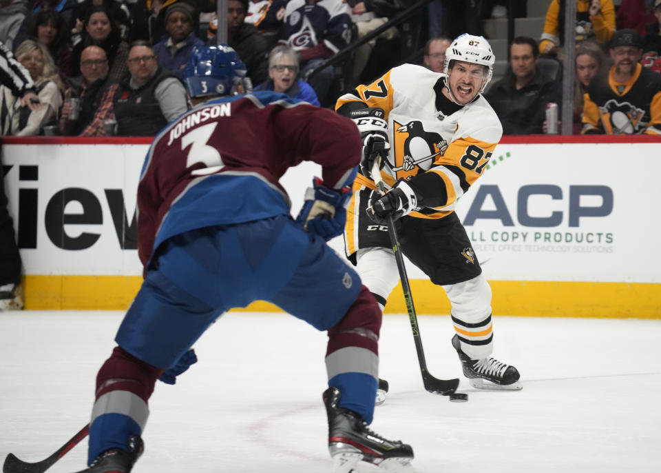 Pittsburgh Penguins center Sidney Crosby, back, passes the puck as Colorado Avalanche defenseman Jack Johnson pursues in the second period of an NHL hockey game Wednesday, March 22, 2023, in Denver. (AP Photo/David Zalubowski)