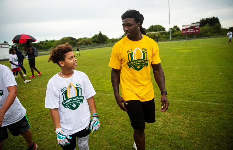 Sammy Watkins, a professional football player for the Green Bay Packers and graduate of South Fort Myers High School walks with Tyronne Dortch,13, while participating in a youth football camp that bears his name at South Fort Myers High School on Thursday, July 14, 2022. Dortch said Watkins was the first NFL football player he had met and that it was a great opportunity to meet him.  