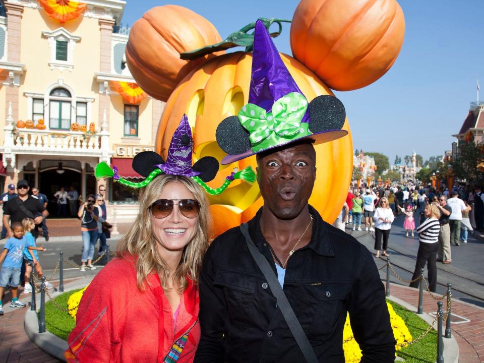 Heidi Klum and Seal wear witch hats and pose in front of a Mickey-shaped pumpkin at Magic Kingdom.
