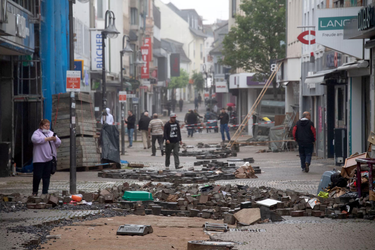 People walk past rubble in a street devastated by the floods in Euskirchen, western Germany, on July 16, 2021. - The death toll from devastating floods in Europe soared to at least 93, most of them in western Germany, where emergency responders were searching for hundreds of missing people. (Photo by SEBASTIEN BOZON / AFP) (Photo by SEBASTIEN BOZON/AFP via Getty Images)