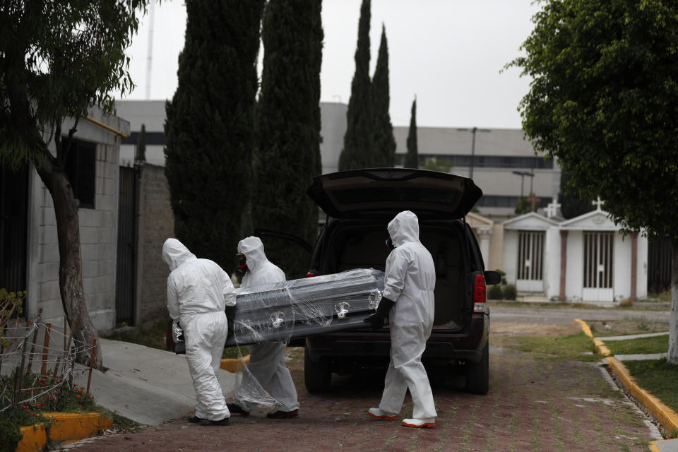 Trabajadores con equipo de protección cargan el ataúd de una persona que se cree murió del coronavirus el jueves 21 de mayo de 2020, en el Mausoleo San Cristóbal en Ecatepec, México. (AP Foto/Rebecca Blackwell)