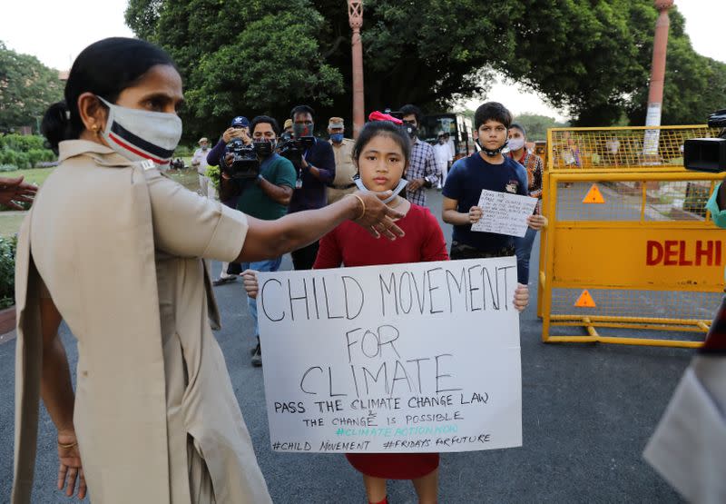 Licypriya Kangujam carrying a placard is stopped by a policewoman during a protest demanding to pass a climate change law outside the parliament in New Delhi