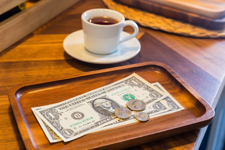 A tip of several dollar bills and coins left on a table