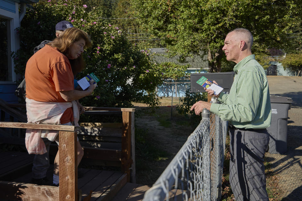 Democrat Paddy McGuire, Mason County auditor, talks with a resident Sandra Nielson while canvassing for the upcoming election, Thursday, Oct. 13, 2022, in Shelton, Wash. (AP Photo/John Froschauer)