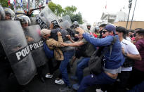 Supporters of ousted President Pedro Castillo clash with police during a protest in Lima, Peru, Thursday, Dec. 8, 2022. Peru's Congress voted to remove Castillo from office Wednesday and replace him with the vice president, shortly after Castillo tried to dissolve the legislature ahead of a scheduled vote to remove him. (AP Photo/Fernando Vergara)