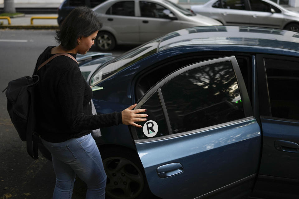 Department store buyer Maria Arreaza gets in a Ridery car she requested, outside her work in Caracas, Venezuela, Thursday, May 5, 2022. Arreaza, 39, had long depended on public transportation to reach her downtown office and was intrigued by advertisements for the new Ridery app, though initially skeptical, she is now a frequent user of Ridery. (AP Photo/Matias Delacroix)