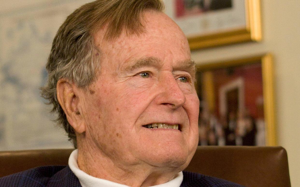 Former President George H.W. Bush smiles as he listens to Republican presidential candidate Mitt Romney speak in Houston, Texas - Reuters