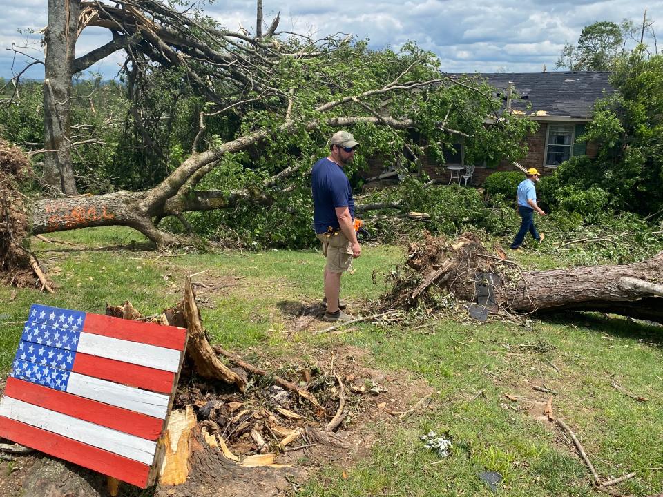 Brandon Park with Maury County Sheriff’s Department, left and Donald Castillo, right, with Knights of Columbus in Maury County work to cut and move trees following tornado damage on Wednesday.