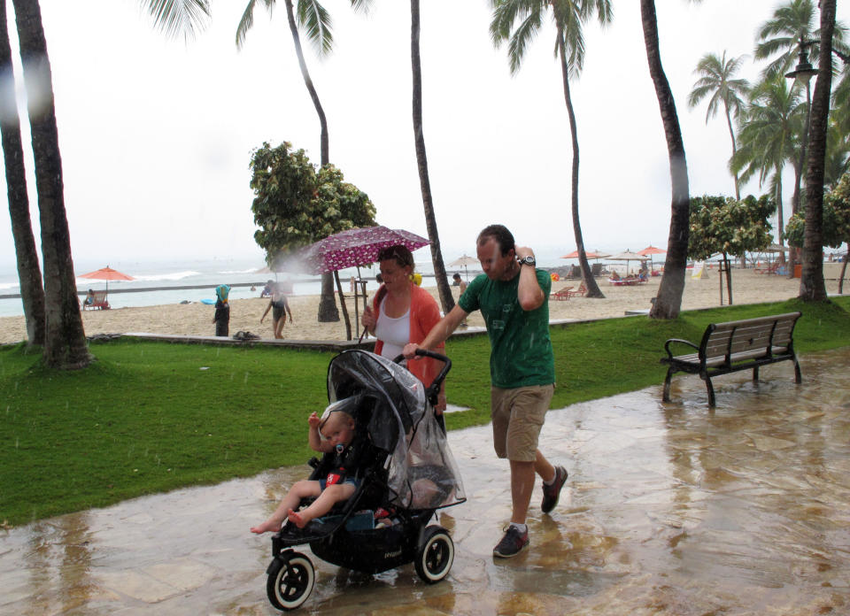 Pedestrians walk along Waikiki beach in Honolulu on Monday, July 29, 2013 as Tropical Storm Flossie approached Hawaii. The storm faded through the morning, but forecasters were still warning residents and tourists to brace for possible flooding, wind gusts, mudslides and big waves. (AP Photo/Audrey McAvoy)