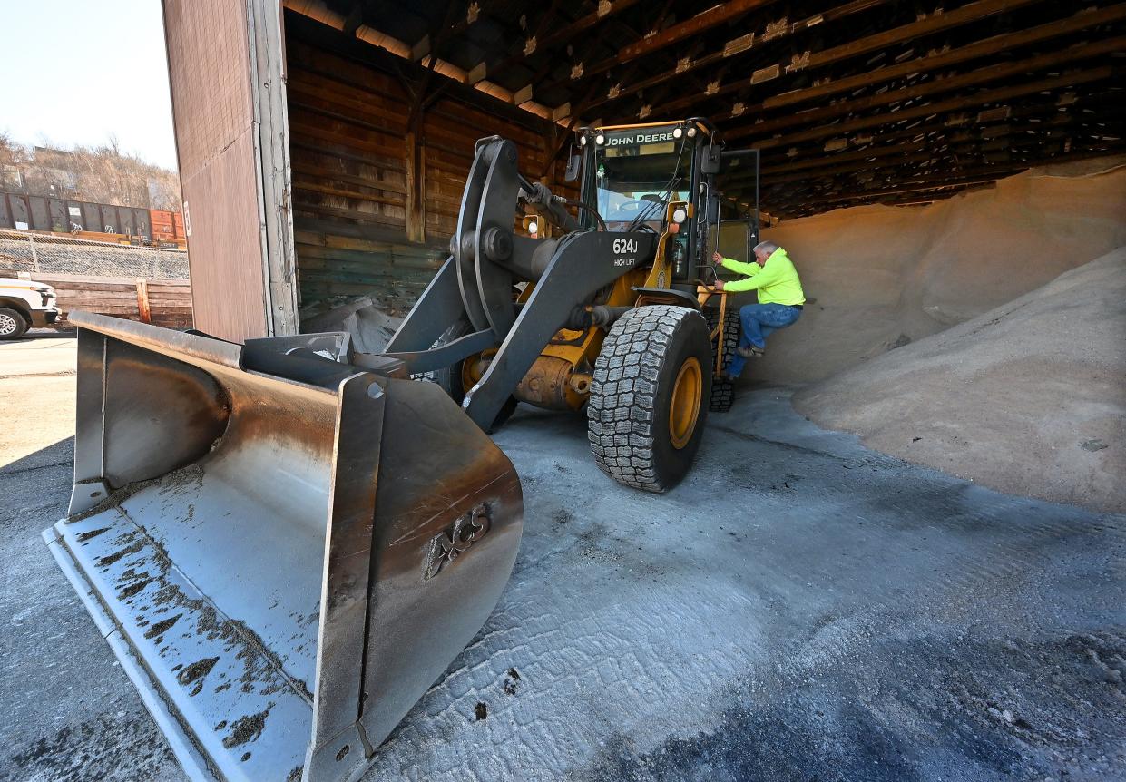 Paul Snape climbs into his excavator to move road salt further back in the salt shed at the Worcester Department of Public Works & Parks on Albany Street Friday morning.