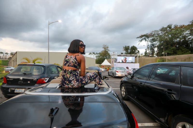 A woman sits on a car to watch "Living in bondage" movie at a drive-in cinema, following the relaxation of lockdown, amid the coronavirus disease (COVID-19) outbreak in Abuja