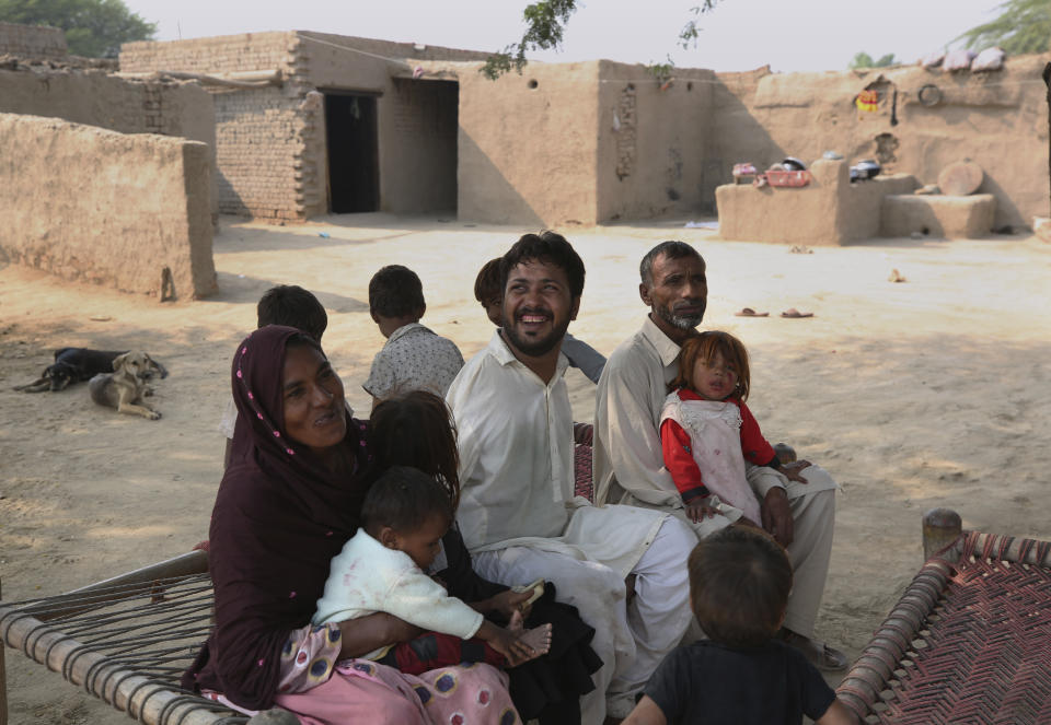 Mohammad Ikram, who play snooker with his chin, sits with his family members at their home in a village near Samundri town, Pakistan, Sunday, Oct. 25, 2020. Ikram, 32, was born without arms, but everyone simply admires his snooker skills when he hits the cue ball with his chin and pots a colored ball on a snooker table. He lives in a remote rural town of Punjab province and his physical disability doesn't come in his way to fulfill his childhood dream of playing the game of snooker. (AP Photo/Anjum Naveed)