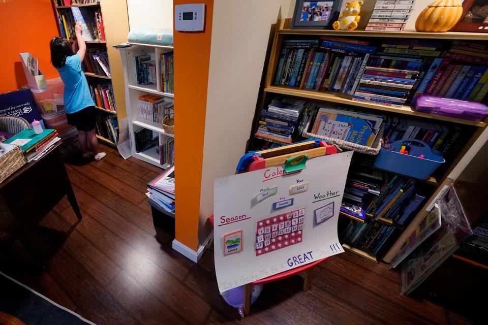 Lily Osgood, 7, selects a book to read from the family library of nearly 2,000 books she shares with her brother, Noah, Tuesday, July 20, 2021, in Fairfax, Vt. The Osgood children will continue to be homeschool this upcoming school year. As the pandemic took hold across the United States in the spring of 2020, it brought disruption and anxiety to most families. Yet some parents are grateful for one consequence: they are now opting to homeschool their children even as schools plan to resume in-person classes. (AP Photo/Charles Krupa)