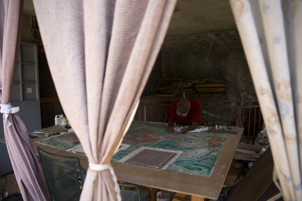 In this July 1, 2019 photo, Haitian artist Franck Louissaint works on the renovation of an earthquake damaged painting by Haitian artist Robert Saint Bruce, at the Musée d'Art du Collège Saint Pierre, in Port-au-Prince, Haiti. The 2010 quake also devastated other museums and galleries across Haiti, with $30 million in losses reported at the Musée Galerie d'Art Nader, which had had one of the world's most extensive collections of Haitian art. (AP Photo/Dieu Nalio Chery)