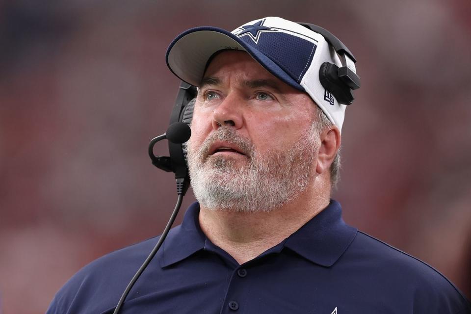 A white man wearing a blue shirt looks slightly up. He is wearing a blue and white hat with a blue star on it. 