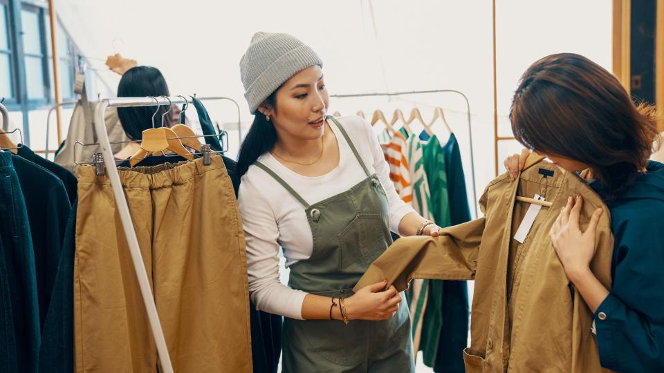 Retail shop clerk helping a mid adult woman customer shop for clothing in a boutique in Japan.