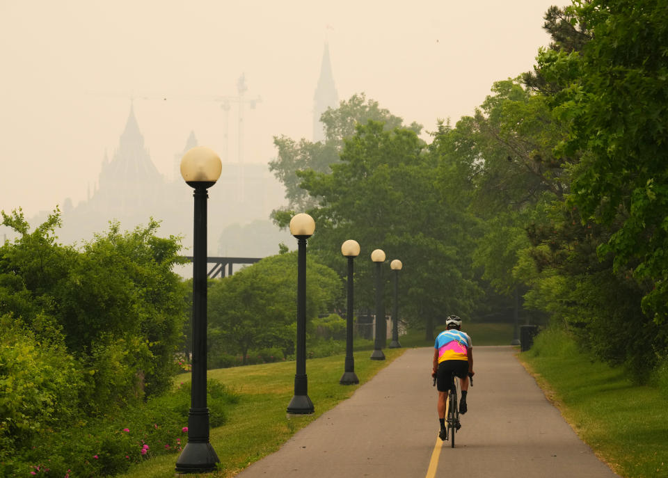 A cyclist rides as smoke from wildfires in Ontario and Quebec obscures Parliament Hill in Ottawa on Tuesday, June 6, 2023. THE CANADIAN PRESS/Sean Kilpatrick