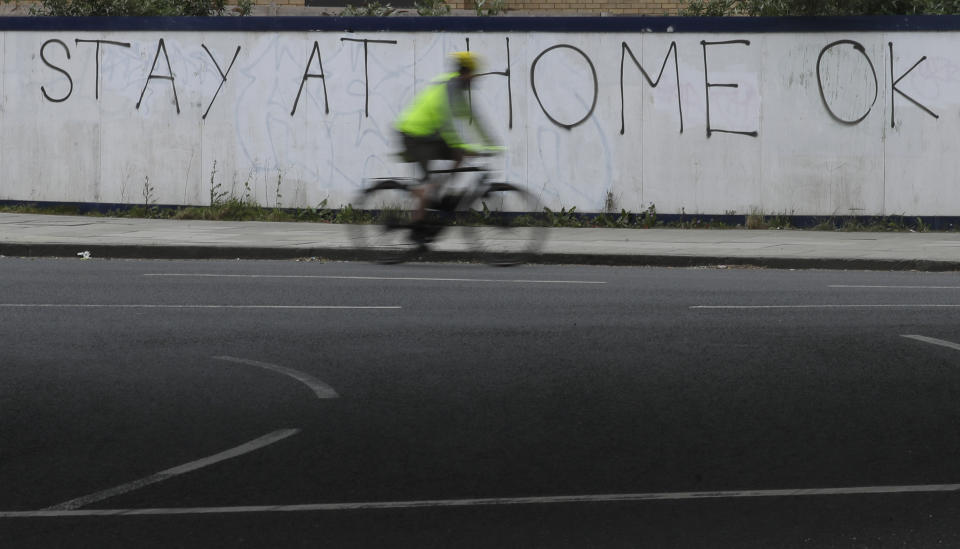 A cyclist passes graffiti as the country continues in lockdown to help curb the spread of the coronavirus, in London, Monday, April 13, 2020. The new coronavirus causes mild or moderate symptoms for most people, but for some, especially older adults and people with existing health problems, it can cause more severe illness or death. (AP Photo/Kirsty Wigglesworth)