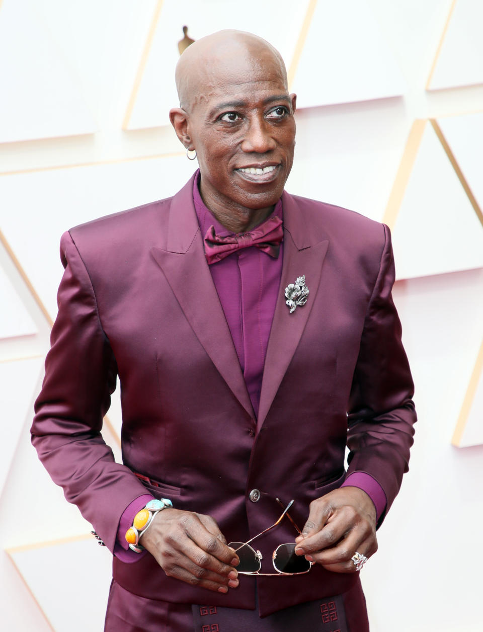 Close-up of Wesley smiling in a suit and bow tie at a media event