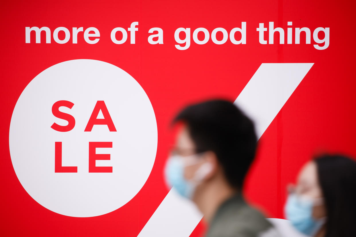 People wearing face masks walk past a sale sign on Oxford Street in London. Photo: David Cliff/NurPhoto via Getty Images