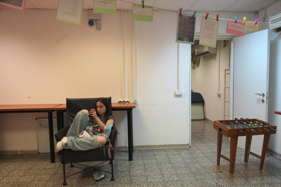 An Israeli girl uses her mobile phone as she takes cover in a public shelter from rockets fired from the Gaza Strip in Ashkelon, Wednesday, May 10, 2023. Palestinian militants fired dozens of rockets from the Gaza Strip into Israel on Wednesday, in a first response to Israeli airstrikes that have killed at least 19 Palestinians, including three senior militants and at least 10 civilians. (AP Photo/Tsafrir Abayov)