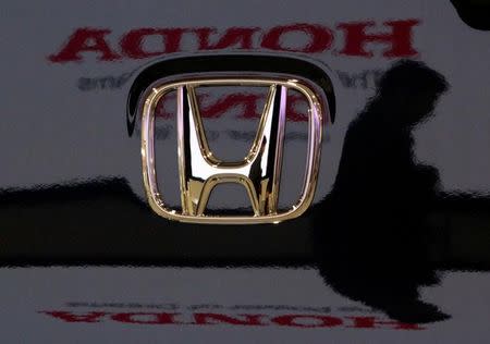 A visitor and the logo of Honda Motor Co are reflected on a Honda car at the company's headquarters in Tokyo January 30, 2009. REUTERS/Toru Hanai/File Photo