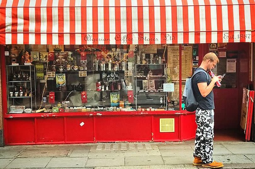 A man looks at his phone outside a coffee supplies store