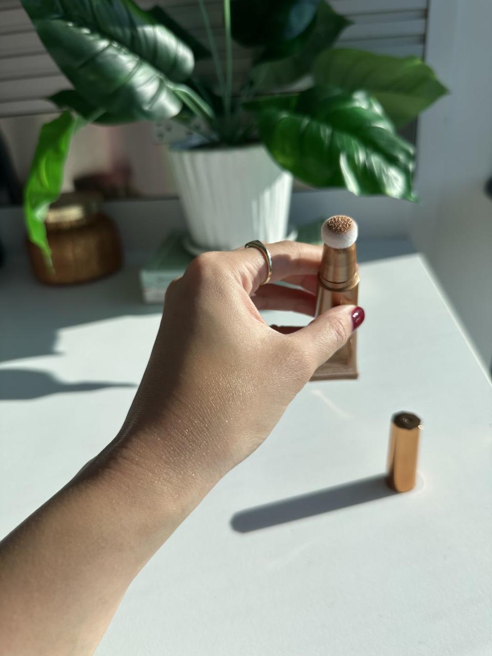 a swatch of the charlotte tilbury beauty wand in shade goldgasm and its packaging