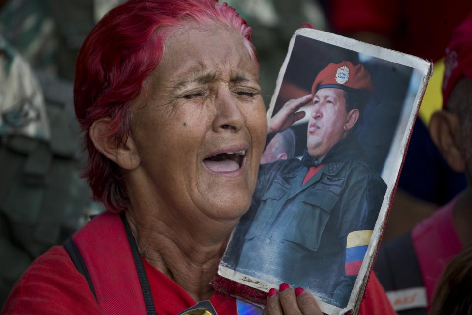 A supporter of Venezuela's President Nicolas Maduro sings a song about the late President Hugo Chavez as she holds an image depicting him during a government rally in Caracas, Venezuela, Saturday, March 9, 2019. Demonstrators danced and waved flags on what organizers labeled a “day of anti-imperialism” in a show of defiance toward the United States, which has imposed oil sanctions on Venezuela in an attempt to oust the president. (AP Photo/Ariana Cubillos)